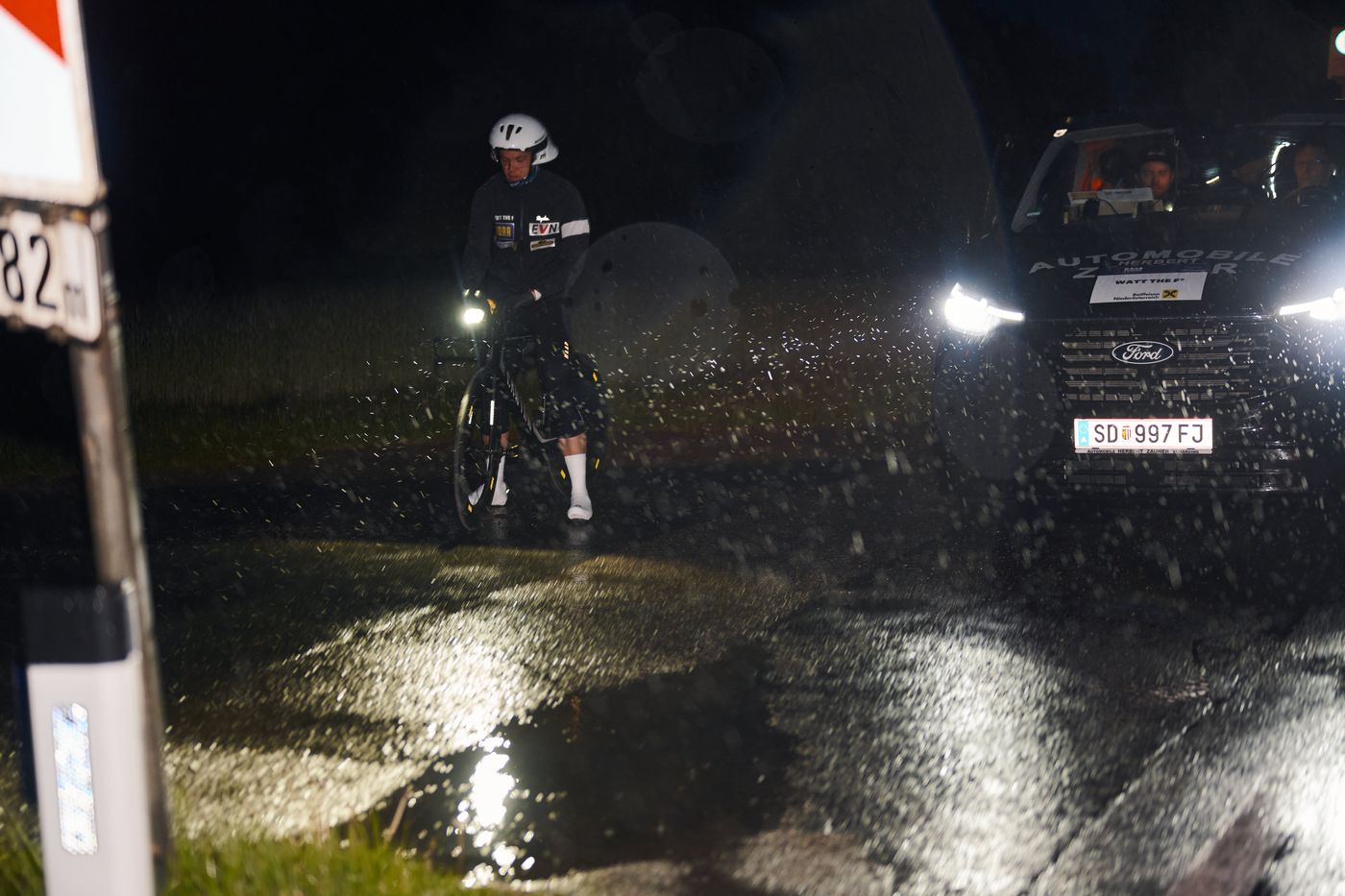 Nachts auf nasser Straße: ein Fahrer im Scheinwerferlicht des Pacecars, der Regen ist im Licht zu sehen