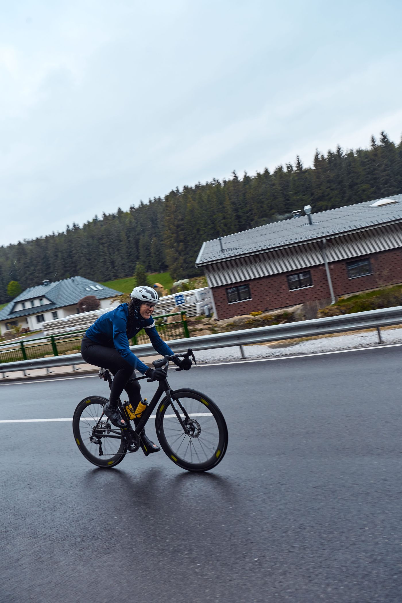 Dani im blauen Trikot auf nasser Straße, Startnummer 211 am Helm, sie grinst